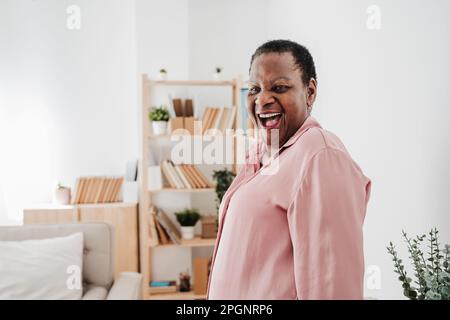 Donna anziana che ride a casa Foto Stock