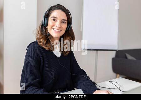 Sorridente imprenditrice che indossa la cuffia in office Foto Stock
