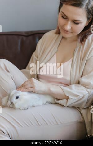 Donna che accarezzava il coniglio in giro a casa Foto Stock