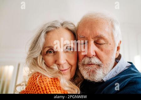 Donna anziana sorridente con l'uomo che si abbraccia a casa Foto Stock