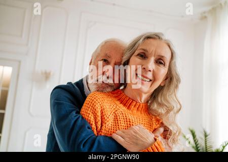 Coppia anziana amorevole che si abbraccia a casa Foto Stock
