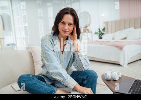 Sorridente freelancer seduto sul divano a casa Foto Stock