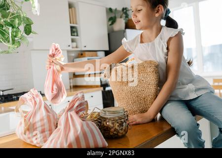 Ragazza con borse riutilizzabili seduta sull'isola della cucina Foto Stock