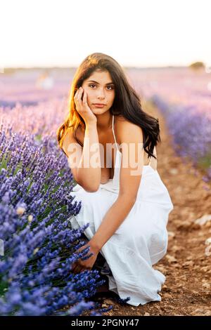 Bella donna accovacciata da piante di lavanda in campo Foto Stock