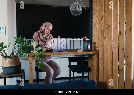 Freelance che indossa un hijab che lavora sul computer portatile in ufficio a casa Foto Stock