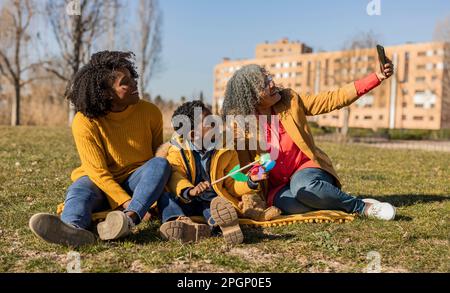 Felice donna anziana che prende selfie con figlia e nipote nel parco Foto Stock