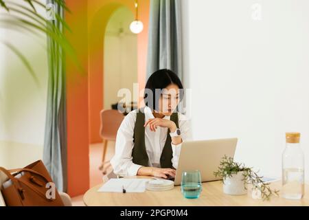 Donna d'affari seria che lavora su un computer portatile in ufficio Foto Stock