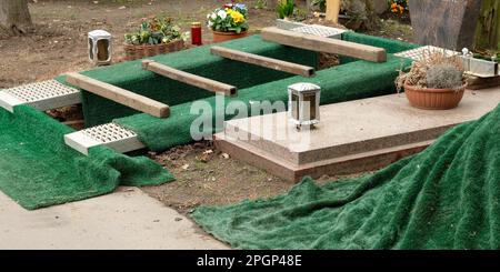 una tomba scavata con tappeti erbosi verdi appena prima di una sepoltura in un cimitero Foto Stock