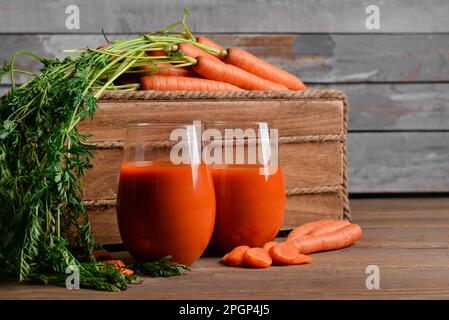 Due bicchieri di succo di carota fresco su un tavolo di legno Foto Stock