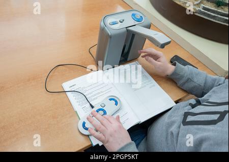 Un uomo ipovedente utilizza una macchina per la scansione e la lettura. Foto Stock