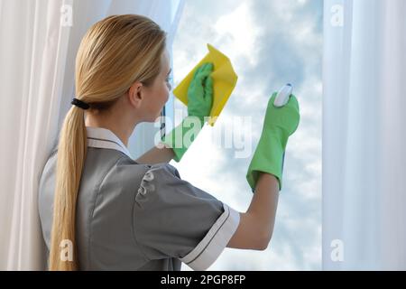 Finestra di pulizia della cameriera con straccio interno, vista posteriore Foto Stock
