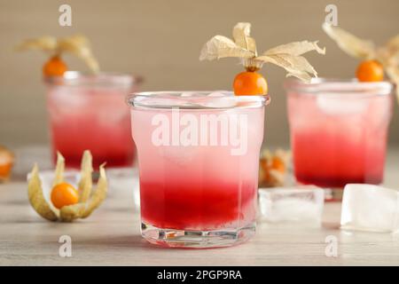 Cocktail rinfrescante decorato con frutta di physalis su un tavolo di legno Foto Stock