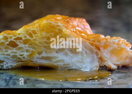 deliziosa e appetitosa struttura porosa di brioche tagliate si muove un po' stirata cosparsa di zucchero a velo versato con sciroppo di fragola accanto a due fragole fresche Foto Stock