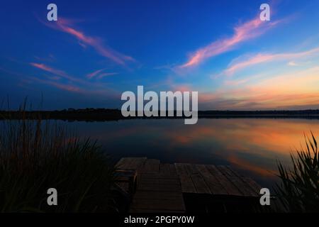 Un tranquillo Lago Blu con uno splendido cielo colorato Foto Stock