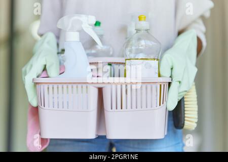 Cestello, secchio e mani che tengono in mano attrezzature per la pulizia e prodotti spray disinfettanti o forniture per l'igiene. Servizio, pulizia e persona o. Foto Stock