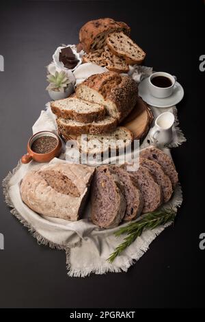 Diversi tipi di pane artigianale su una tavola nera Foto Stock