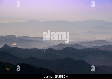 Panorama mozzafiato al tramonto - cielo bianco vibrante, nuvole dinamiche, montagne nebbiose. Oceano sereno che circonda il Villaggio costiero di Jiufen in Taiwan. Foto Stock