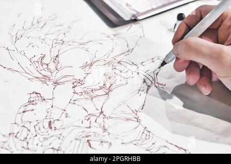 Primo piano della mano di un fumettista che dipinge un personaggio del manga cartoon in un disegno a linee d'inchiostro Foto Stock