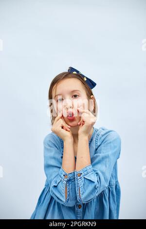 Sorridente bambina fare trend mini segno di cuore con le dita in abito denim casual isolato su sfondo bianco, studio, fa l'icona dell'amore, gesto con Foto Stock