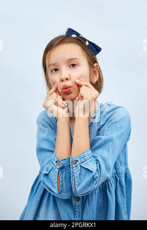 Sorridente bambina fare trend mini segno di cuore con le dita in abito denim casual isolato su sfondo bianco, studio, fa l'icona dell'amore, gesto con Foto Stock