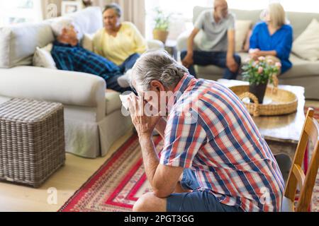 Gruppo di amici anziani emozionali e diversi in soggiorno, parlando durante la sessione di terapia di gruppo. Stile di vita, amicizia e supporto senior. Foto Stock