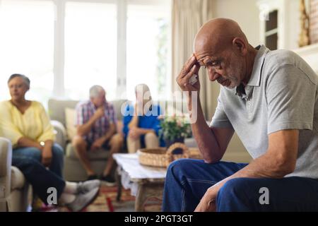 Gruppo di amici anziani emozionali e diversi in soggiorno, parlando durante la sessione di terapia di gruppo. Stile di vita, amicizia e supporto senior. Foto Stock