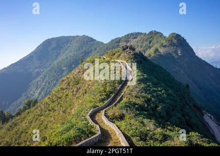 Percorso curvo con muro di pietra a secco conduce sulle montagne e colline a Bandipur Nepal in una giornata di sole con cielo blu. Il sentiero ricorda il Gr Foto Stock