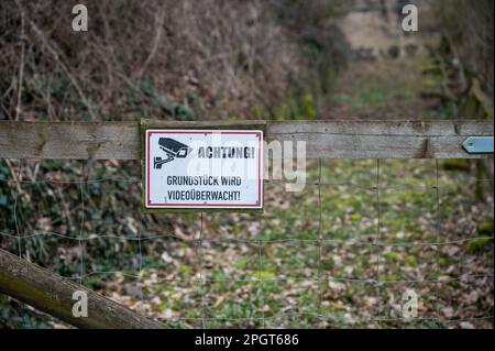 Achtung Grundstueck wird Videoueberwacht si prega di notare che la proprietà è sotto videosorveglianza cartello attaccato ad una recinzione di legno con giardino nel Foto Stock