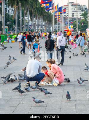 Phnom Penh, Cambogia-Dicembre 23rd 2022: Molte famiglie Khmer e amici, si riuniscono lungo la popolare Riverside Boulevard strip, come il sole tramonta, godendo soc Foto Stock