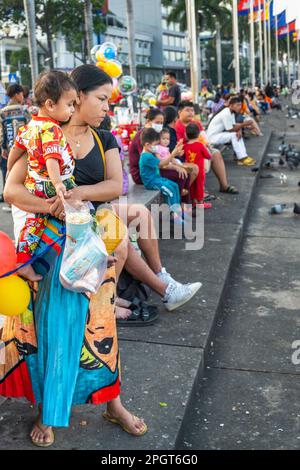 Phnom Penh, Cambogia-Dicembre 23rd 2022:nel freddo relativo del crepuscolo iniziale, molte famiglie, amici e piccioni si siedono lungo il muro di fronte al fiume, a Sisowath Foto Stock