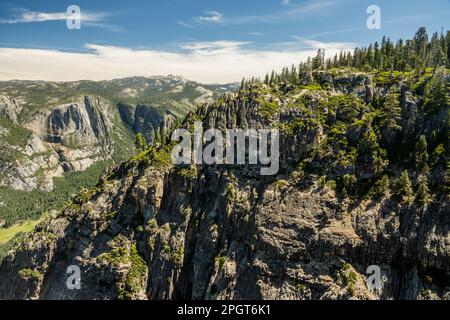 Cascate di Yosemite in lontananza dietro il Muro di Sheer Rock a Taft Point a Yosemite Foto Stock