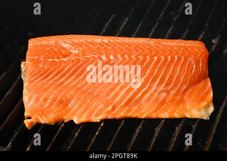 Primo piano con filetto di salmone affumicato e grigliato all'aperto con griglia in ghisa, vista ad angolo Foto Stock