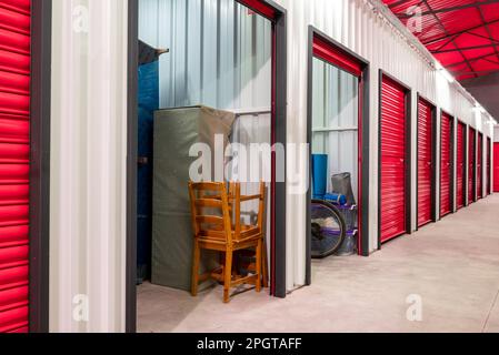 Corridoio dell'unità di self-storage con porte rosse. Unità di stoccaggio a noleggio Foto Stock