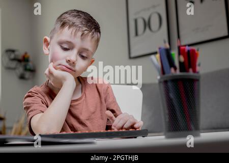 Il ragazzo seduto al tavolo, studiava matematica, si stanca e si appoggiò in mano Foto Stock