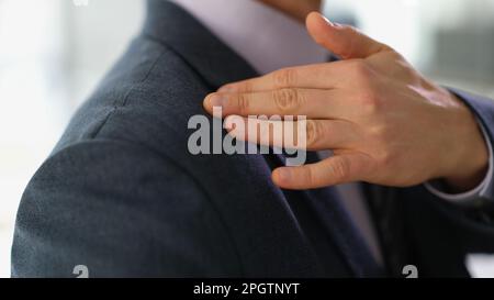 Uomo d'affari in tuta d'affari spazzolando via la polvere o forfora dal suo primo piano della spalla Foto Stock