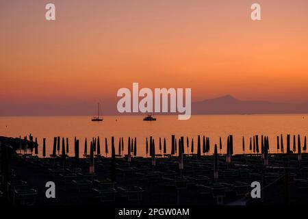 Due navi al tramonto, montagne e lettini sulla spiaggia di Sestri Levante, Liguria. Sfondo estivo Foto Stock