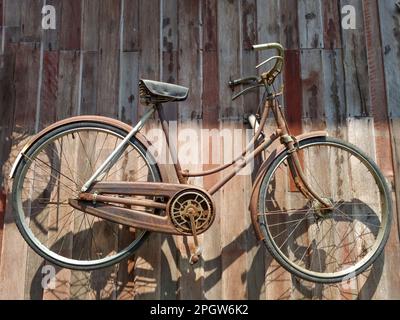 Vecchia bicicletta appesa al muro Foto Stock