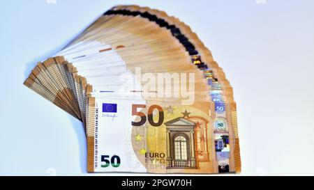 Concetto di molti euro: Un mucchio di banconote arrotolate da 50 euro giacenti su uno sfondo bianco, pila di banconote da 50 euro background commerciale Foto Stock