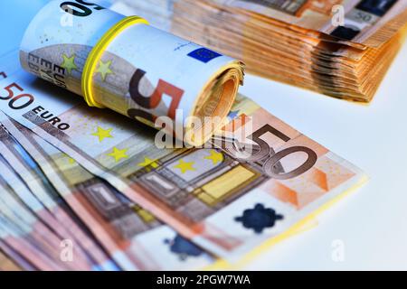 Concetto di molti euro: Un mucchio di banconote arrotolate da 50 euro giacenti su uno sfondo bianco, pila di banconote da 50 euro background commerciale Foto Stock