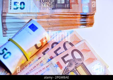 Concetto di molti euro: Un mucchio di banconote arrotolate da 50 euro giacenti su uno sfondo bianco, pila di banconote da 50 euro background commerciale Foto Stock