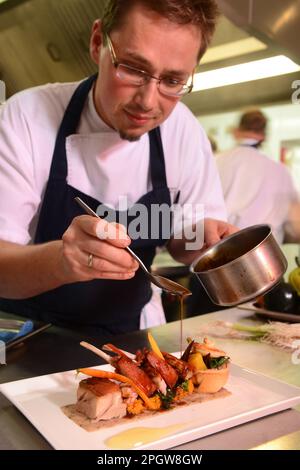 Il capo chef Kuba Winkowski assembla il piatto maiale arrosto con la carota Quinoa al Nest con piume nell'Oxfordshire. Foto Stock