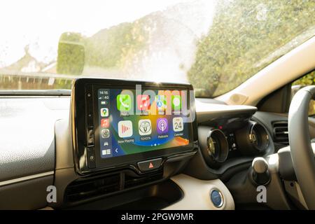 Vista interna di un'auto ibrida di nuova tecnologia di costruzione giapponese. Visualizzazione dell'ampio touch screen integrato del telefono wireless per la navigazione e il controllo delle app. Foto Stock