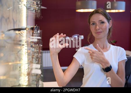 Felice ragazza allegra sta puntando un dito alla sua scelta nel negozio ottico Foto Stock