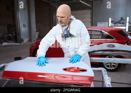 L'uomo di mezza età sul posto di lavoro è impegnato nelle riparazioni delle auto Foto Stock