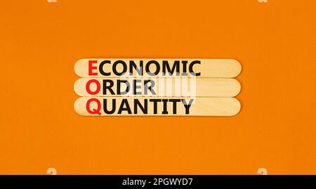 Simbolo quantità ordine economico EOQ. Concetto parole EOQ ordine economico quantità su bastone di legno su una bella tavola arancione sfondo arancione. Business Foto Stock