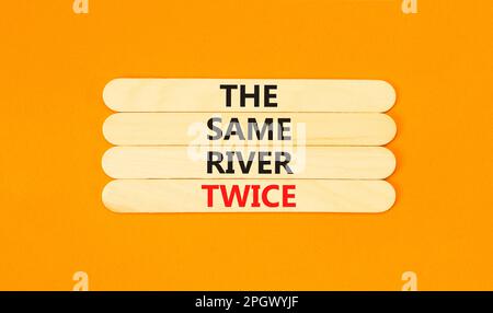 Lo stesso fiume due volte simbolo. Concetto parole lo stesso fiume due volte su bastone di legno. Bella tavola arancione sfondo arancione. Business motivazionale il s Foto Stock