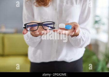 Donna con problemi di vista sta facendo la scelta tra occhiali e lenti a contatto Foto Stock