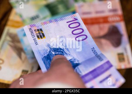 migliaia di corone norvegesi hanno tenuto in mano e messo sul tavolo pieno di banconote, valuta norvegese, finanza e concetto di business Foto Stock