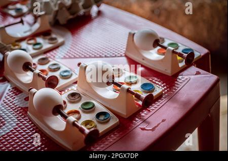 Uova di Pasqua bianche fai da te con strumenti di pittura acquerello su tavolo rosso. Decorazione fatta a mano con uova di Pasqua. Foto Stock