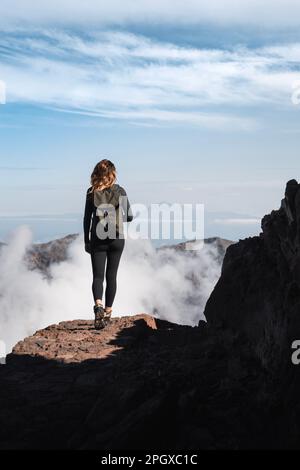 Una ragazza con zaino facendo un'escursione attraverso il sentiero del Roque de los Muchachos nell'isola di la Palma. Foto Stock